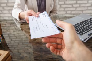 Close-up,Of,A,Business,Woman,Giving,Cheque,To,Her,Colleague